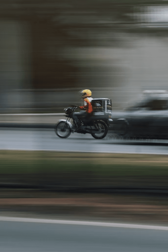 Courier riding a motorbike through a city street